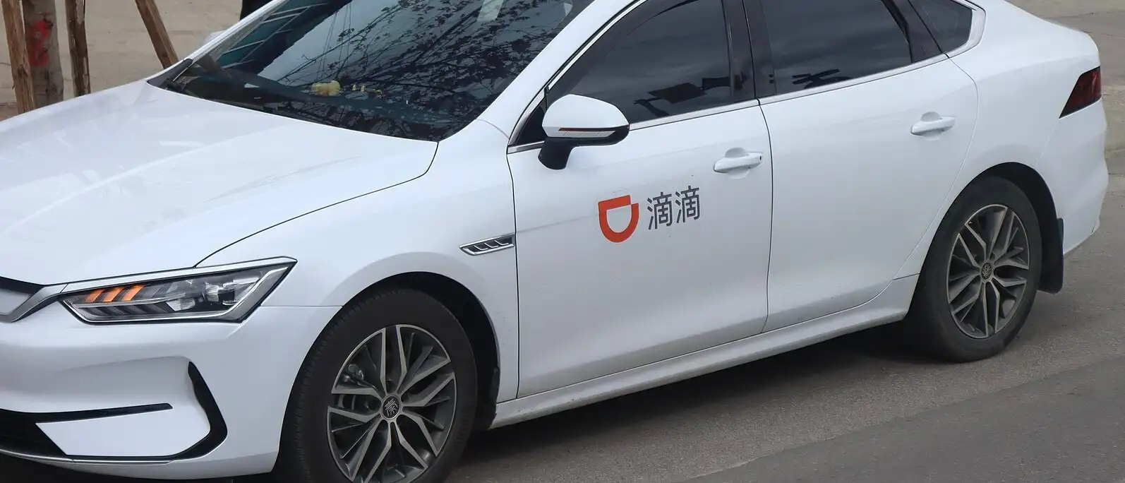 Weißes Fahrzeug mit DiDi-Aufkleber auf der Fahrertür, geparkt am Straßenrand in China